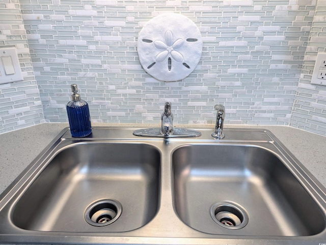 room details featuring light stone counters, sink, and tasteful backsplash