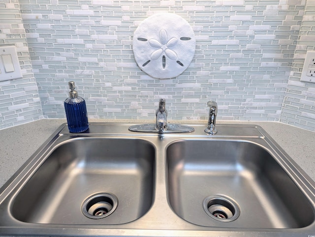 room details featuring light stone counters, backsplash, and a sink