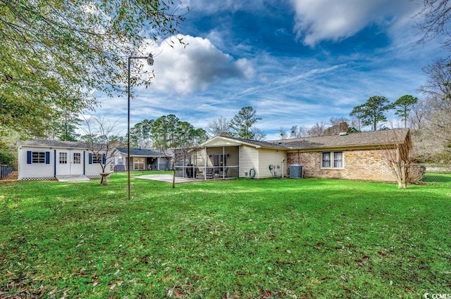 back of house with an outbuilding, a yard, central AC, and a patio