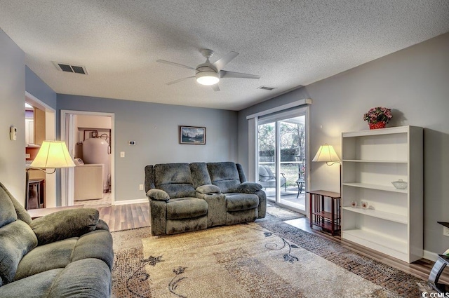 living room with hardwood / wood-style flooring, a textured ceiling, and ceiling fan