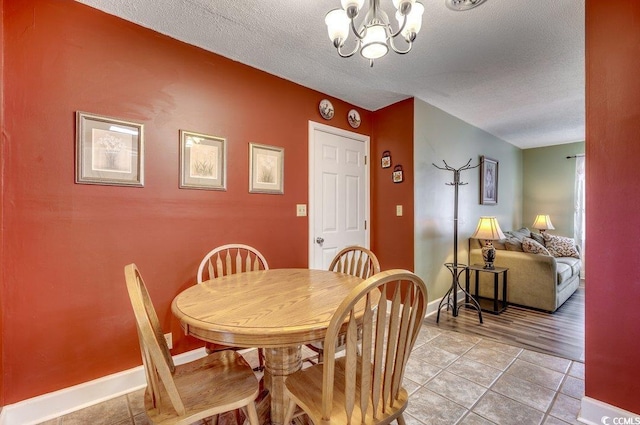 dining space featuring light tile patterned floors, a notable chandelier, and a textured ceiling