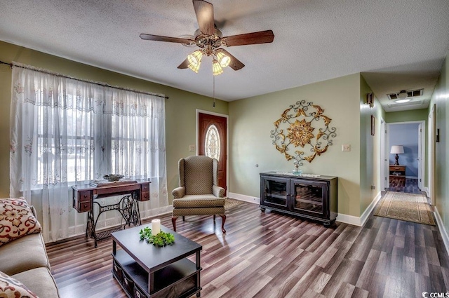 living room featuring hardwood / wood-style flooring, ceiling fan, and a textured ceiling