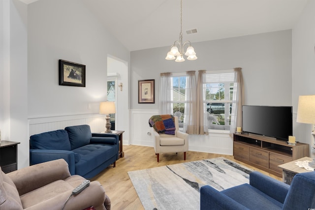 living room featuring vaulted ceiling, an inviting chandelier, and light hardwood / wood-style floors