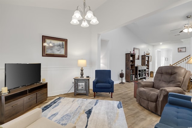 living room with lofted ceiling, ceiling fan with notable chandelier, and light wood-type flooring