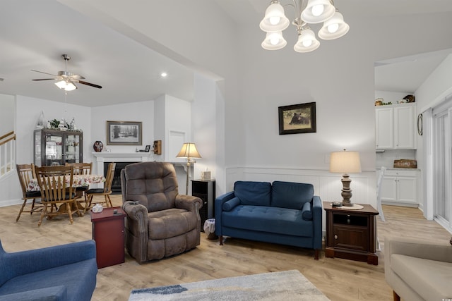 living room featuring ceiling fan with notable chandelier, vaulted ceiling, and light hardwood / wood-style floors