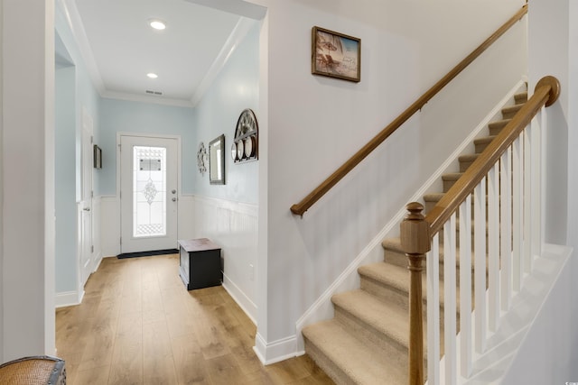 entryway with ornamental molding and light hardwood / wood-style floors