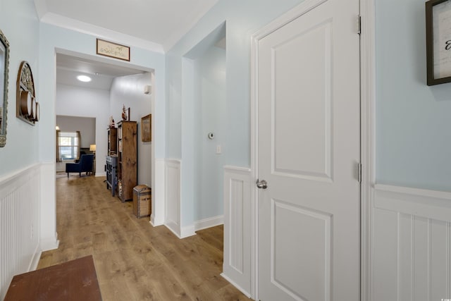 hall with ornamental molding and light wood-type flooring