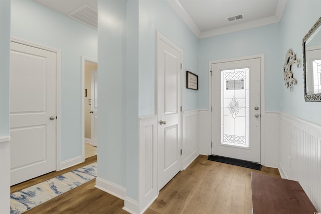 entryway featuring ornamental molding, a wealth of natural light, and light hardwood / wood-style floors