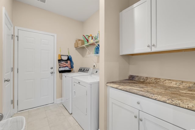 washroom with light tile patterned floors, cabinets, and washing machine and clothes dryer