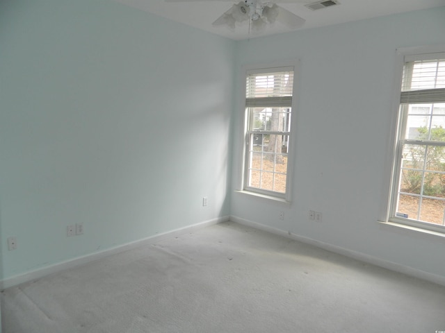 spare room with a healthy amount of sunlight, light colored carpet, and ceiling fan