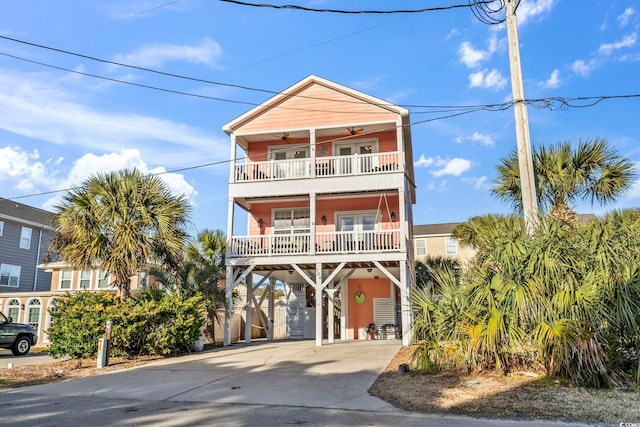 raised beach house with a carport, driveway, ceiling fan, and a balcony