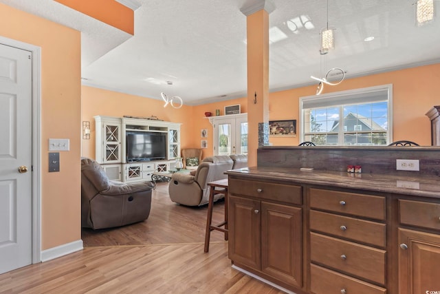 kitchen with open floor plan, pendant lighting, baseboards, and light wood-style floors