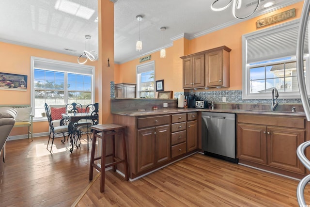 kitchen with wood finished floors, a sink, a wealth of natural light, dishwasher, and crown molding