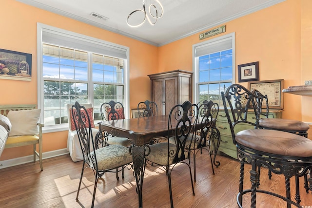 dining room with ornamental molding, visible vents, baseboards, and wood finished floors