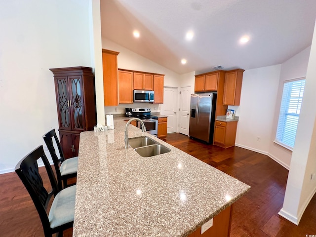 kitchen featuring a breakfast bar, sink, light stone counters, kitchen peninsula, and stainless steel appliances