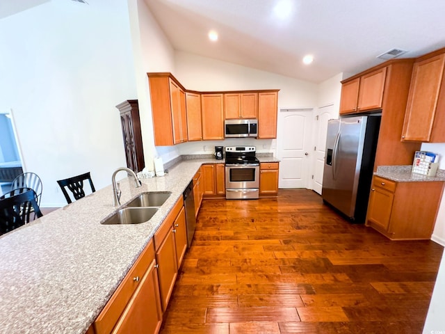 kitchen with sink, a breakfast bar area, appliances with stainless steel finishes, dark hardwood / wood-style floors, and light stone counters