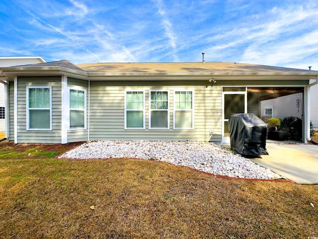 back of property with a lawn and a patio area