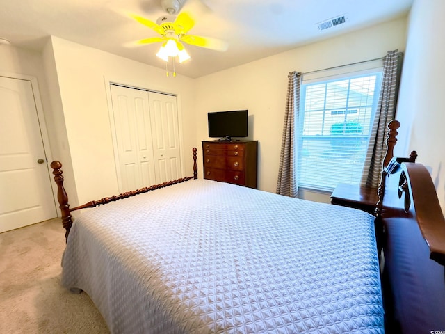 bedroom featuring light carpet, ceiling fan, and a closet