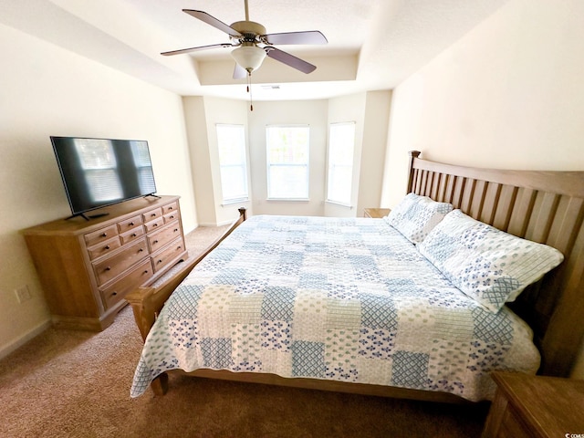 bedroom featuring ceiling fan, light colored carpet, and a tray ceiling