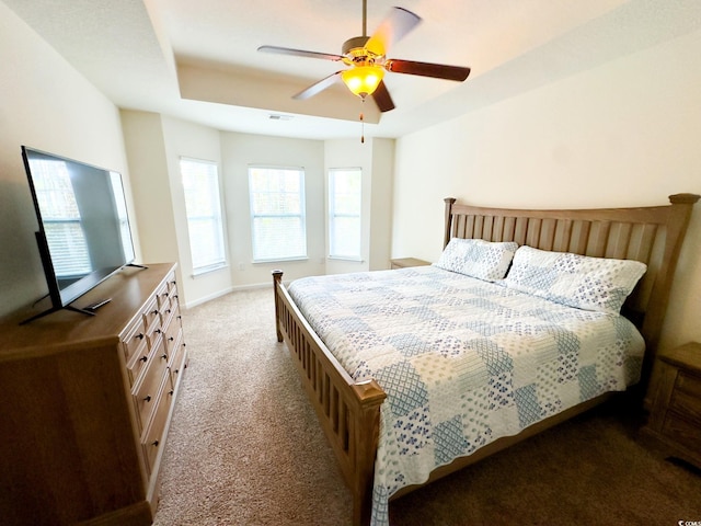 bedroom with ceiling fan, a raised ceiling, and light carpet