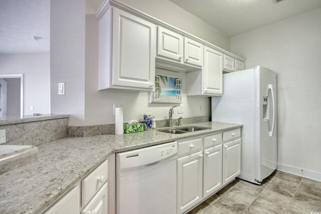 kitchen with white cabinetry, sink, white appliances, and light stone counters