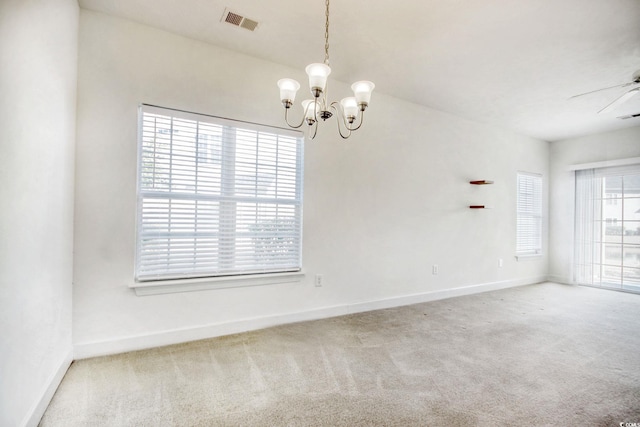 carpeted empty room featuring ceiling fan with notable chandelier