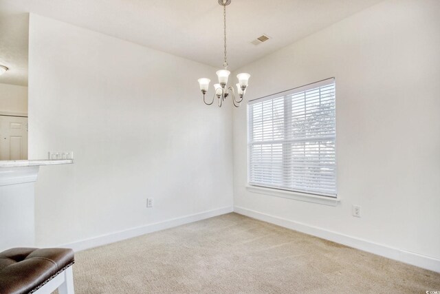 carpeted empty room featuring a notable chandelier