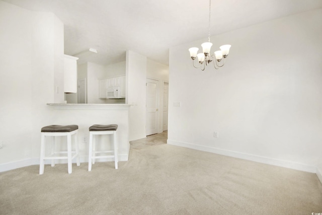 interior space with pendant lighting, white cabinetry, a kitchen breakfast bar, light carpet, and kitchen peninsula