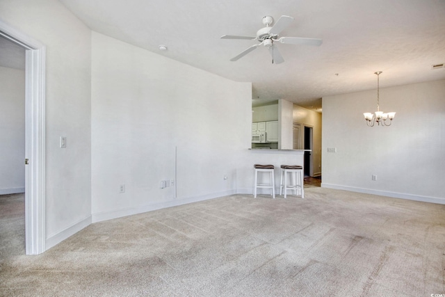 unfurnished living room with light colored carpet and ceiling fan with notable chandelier