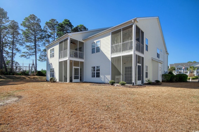 back of house with ceiling fan and a lawn