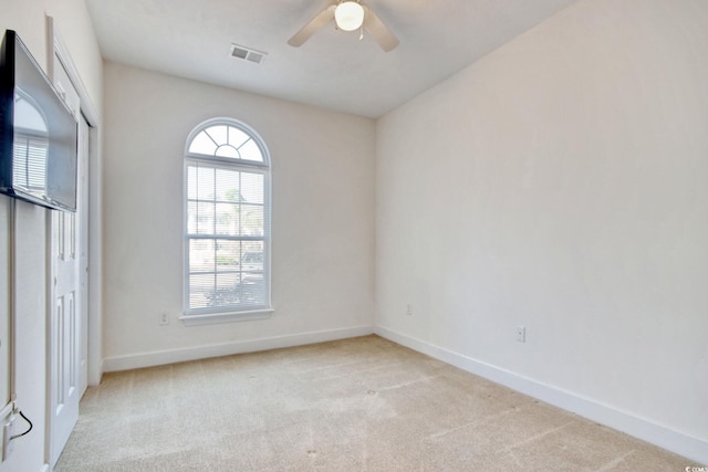 spare room featuring light carpet and ceiling fan