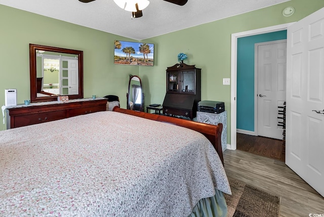 bedroom with ceiling fan, light hardwood / wood-style floors, and a textured ceiling