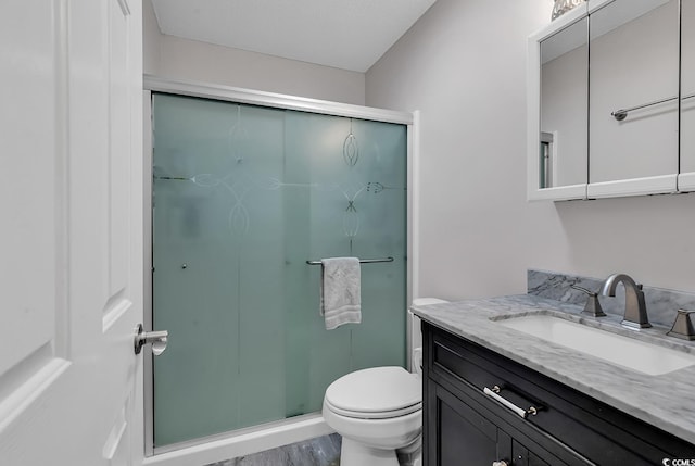 bathroom featuring vanity, hardwood / wood-style floors, a shower with door, and toilet