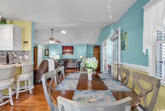 dining area with lofted ceiling, hardwood / wood-style flooring, a textured ceiling, and ceiling fan