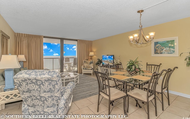 dining space featuring baseboards, a chandelier, a textured ceiling, and light tile patterned flooring