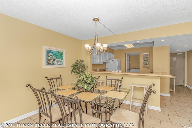 dining room with light tile patterned floors, a textured ceiling, a chandelier, and baseboards