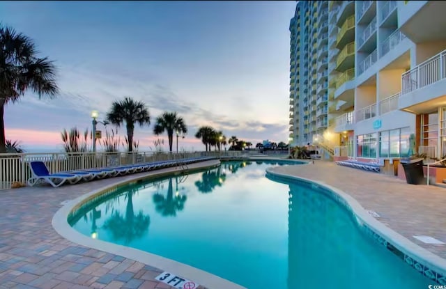 pool at dusk featuring a patio area