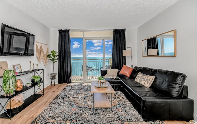 living room with hardwood / wood-style floors, a textured ceiling, and a water view