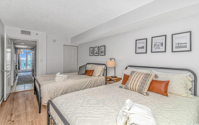 bedroom featuring a closet, a textured ceiling, and light wood-type flooring