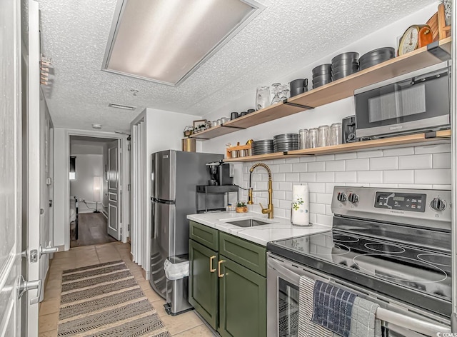 kitchen with electric stove, green cabinetry, sink, and light tile patterned floors