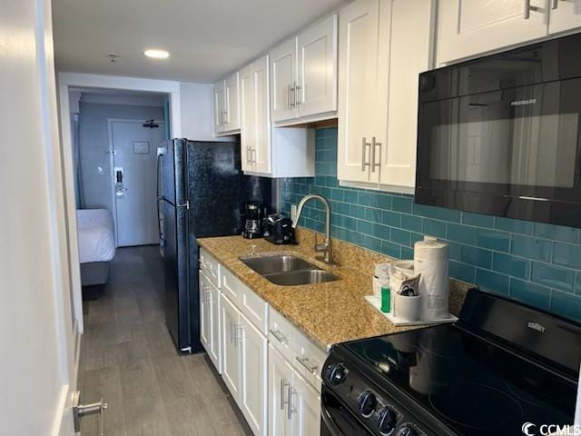 kitchen featuring white cabinets, a sink, black appliances, and light stone countertops