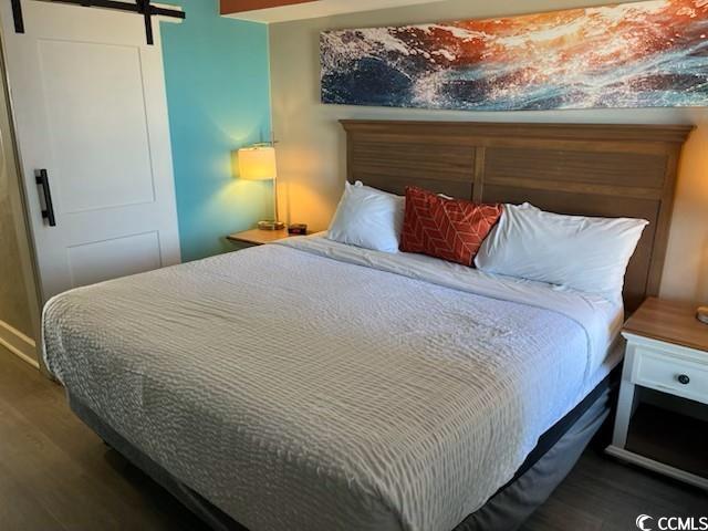 bedroom with a barn door and wood finished floors