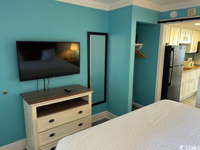 bedroom with ornamental molding, freestanding refrigerator, and baseboards