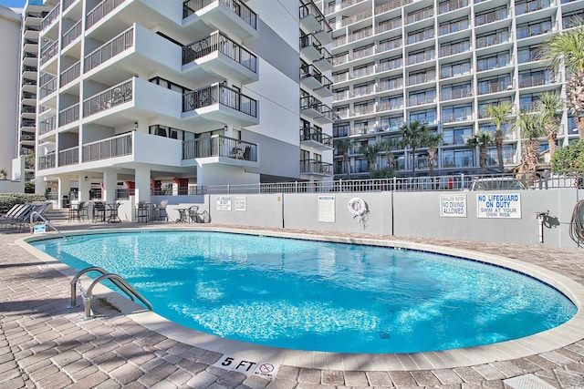 pool with a patio area and fence