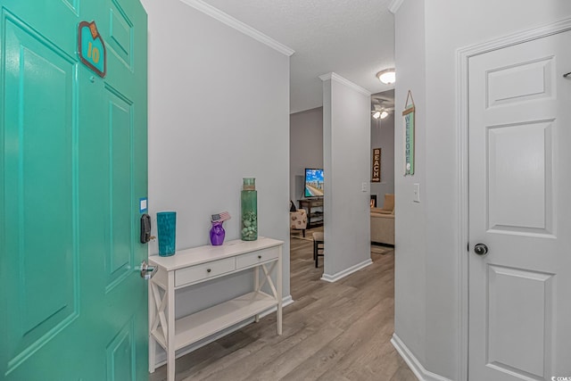 entryway with ornamental molding, light wood-style floors, a ceiling fan, a textured ceiling, and baseboards