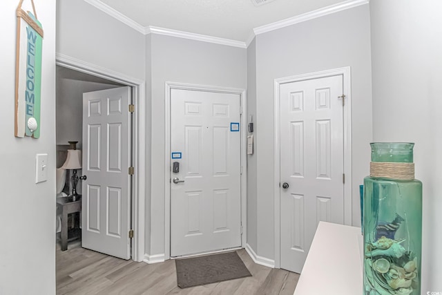 foyer with ornamental molding, baseboards, and light wood finished floors