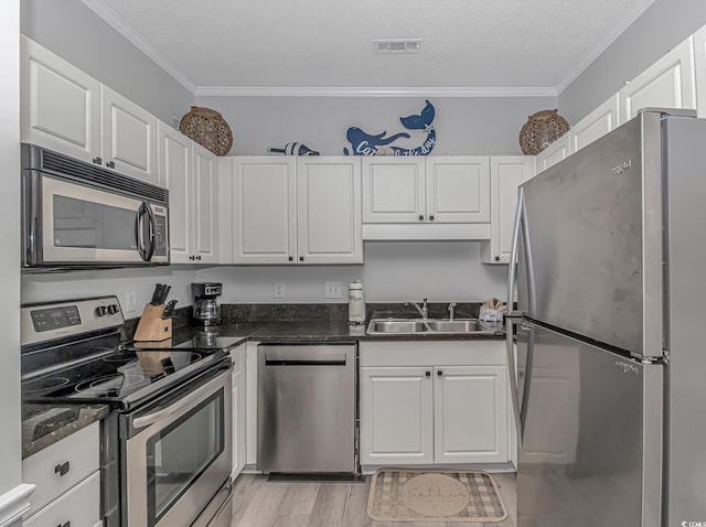 kitchen with appliances with stainless steel finishes, a sink, visible vents, and white cabinets