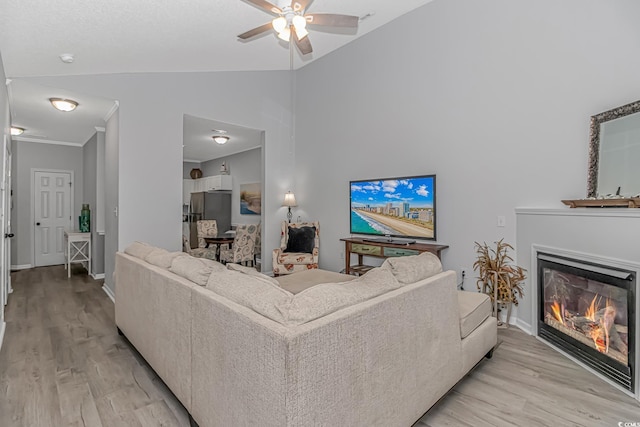 living room featuring light wood-style flooring, baseboards, a ceiling fan, and a glass covered fireplace