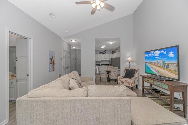 living area featuring lofted ceiling, light wood-type flooring, visible vents, and ceiling fan