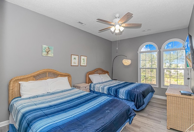 bedroom featuring a textured ceiling, light wood-type flooring, visible vents, and baseboards